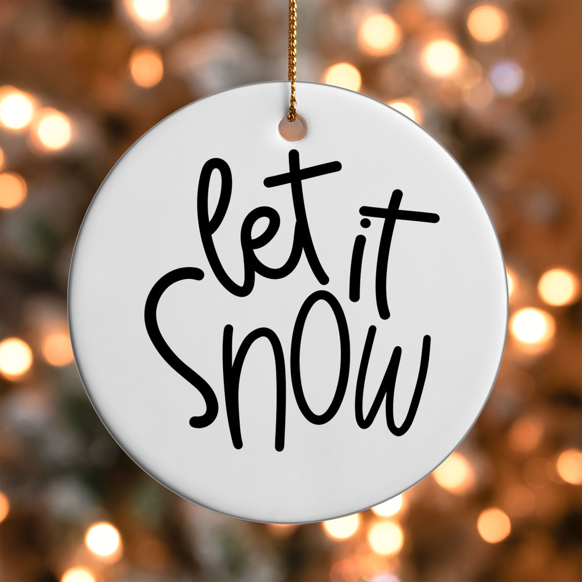 Let It Snow ornament UV DTF transfer on a round white ornament with a bokeh light background
