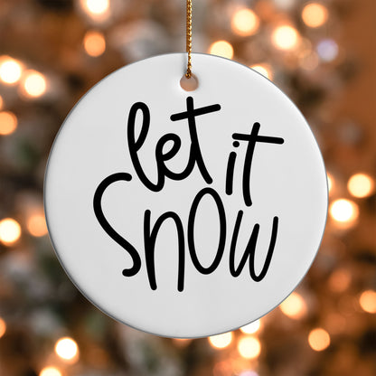 Let It Snow ornament UV DTF transfer on a round white ornament with a bokeh light background