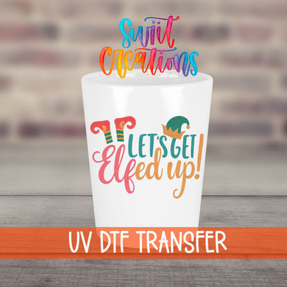 Let's Get Elfed Up UV DTF transfer on a white shot glass in front of a brick wall