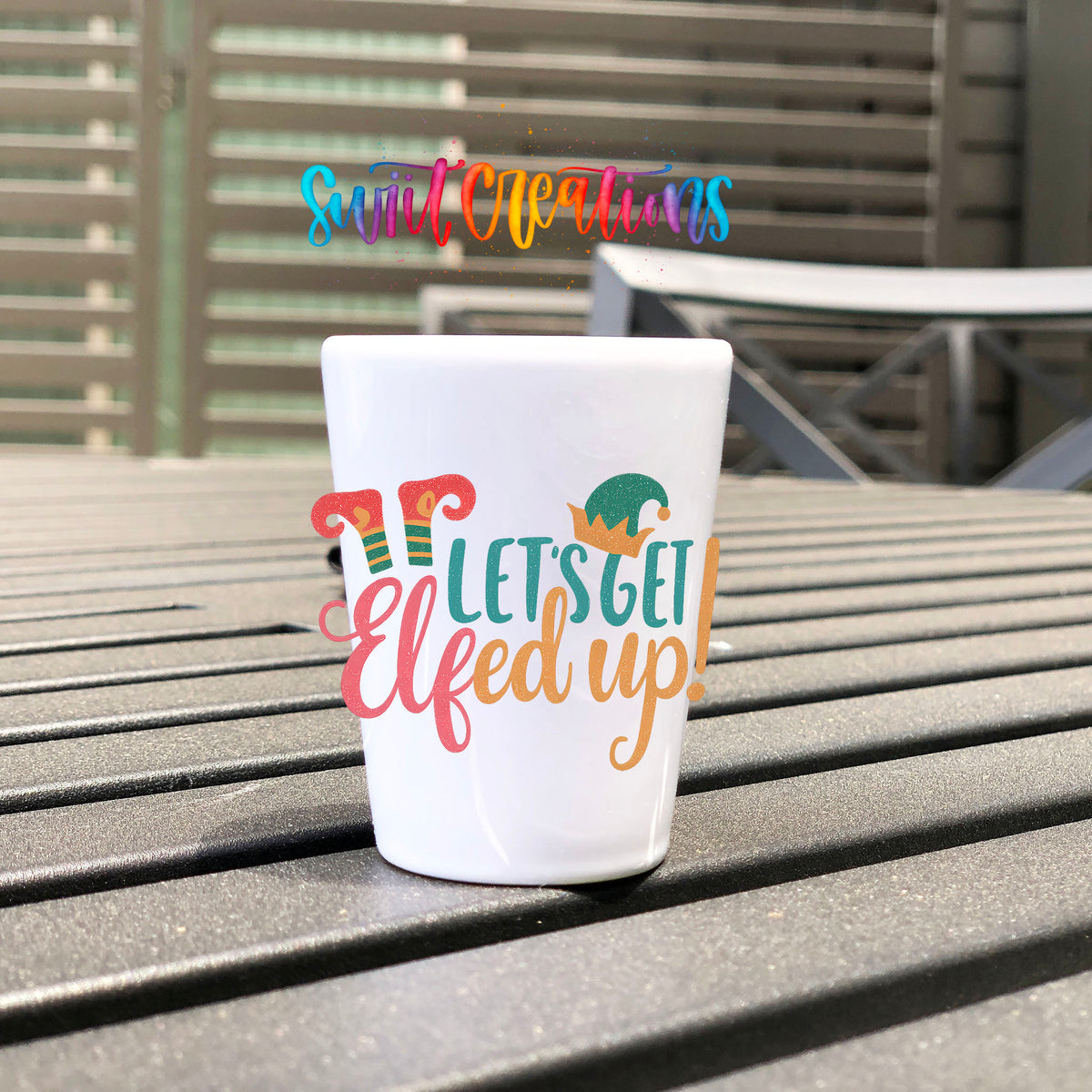 Let's Get Elfed Up UV DTF transfer on a white shot glass on an outdoor patio table