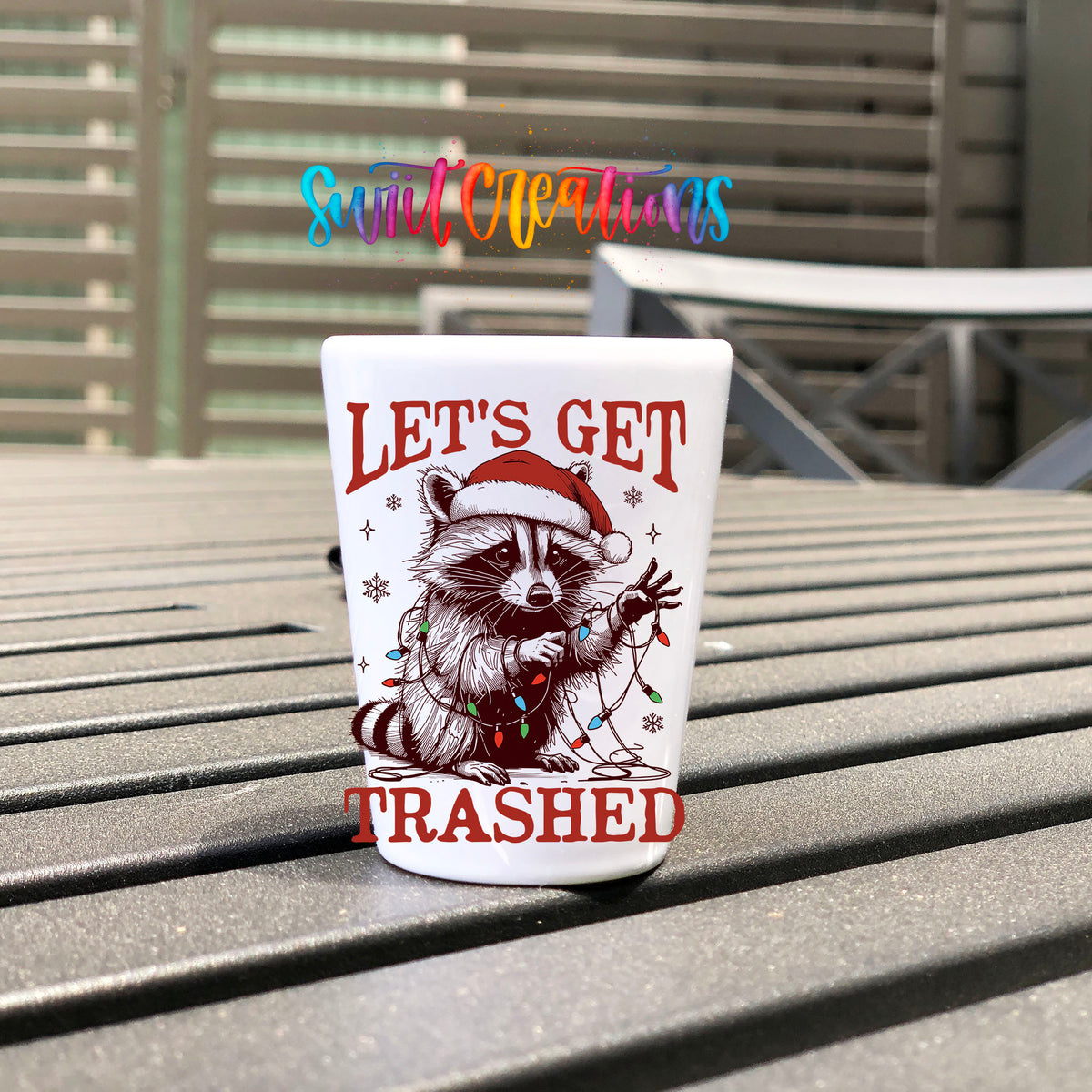 Let's Get Trashed Christmas UV DTF transfer on a white shot glass on an outdoor patio table