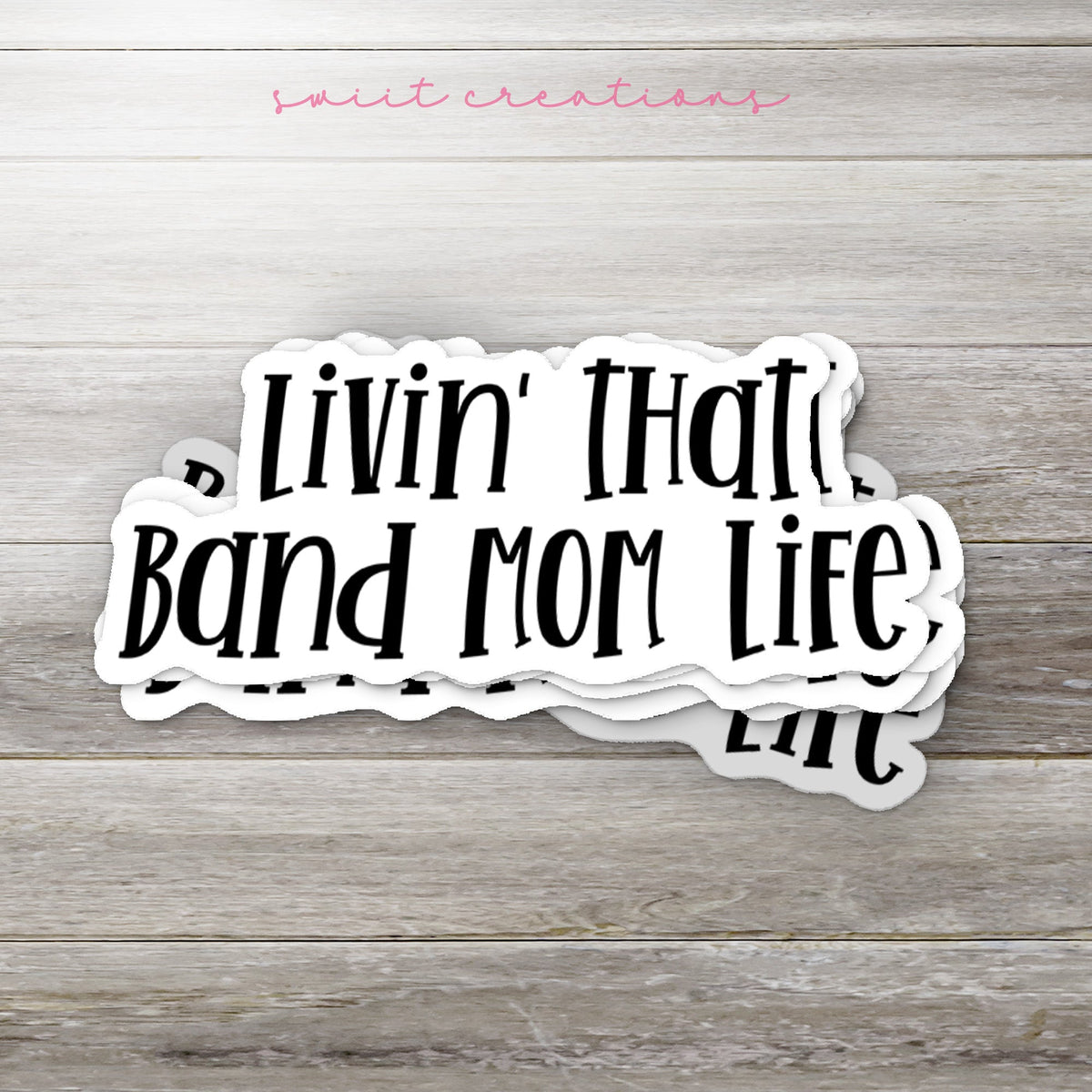 Stack of Black Band Mom Life glossy stickers on a gray wood table