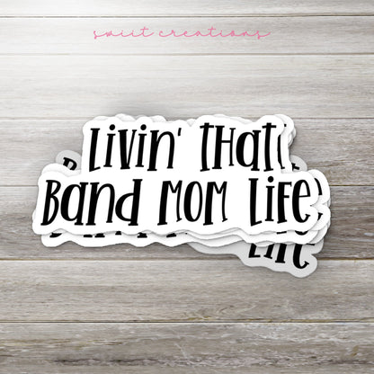 Stack of Black Band Mom Life glossy stickers on a gray wood table