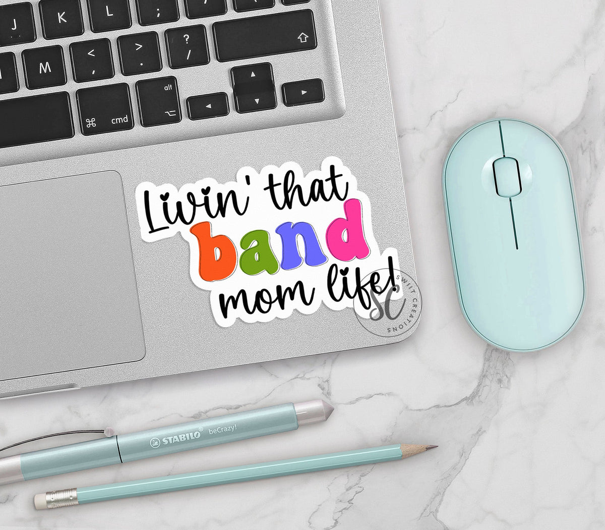 Rainbow Band Mom Life vinyl sticker on a silver laptop next to a mint mouse and pens