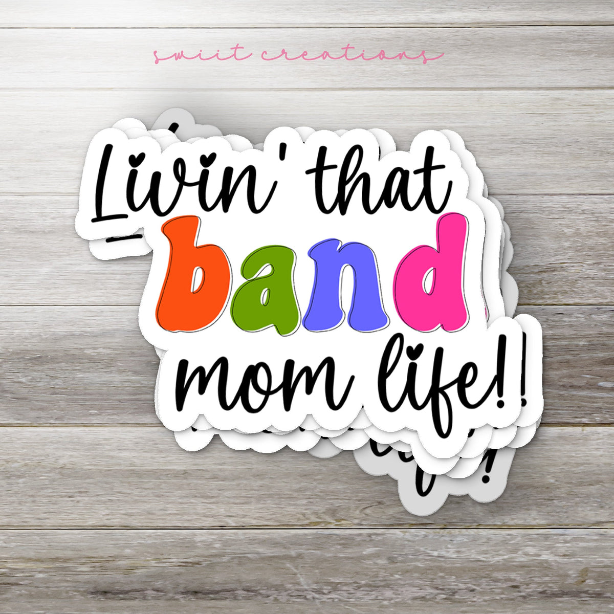 Stack of Rainbow Band Mom Life glossy stickers on a gray wood table