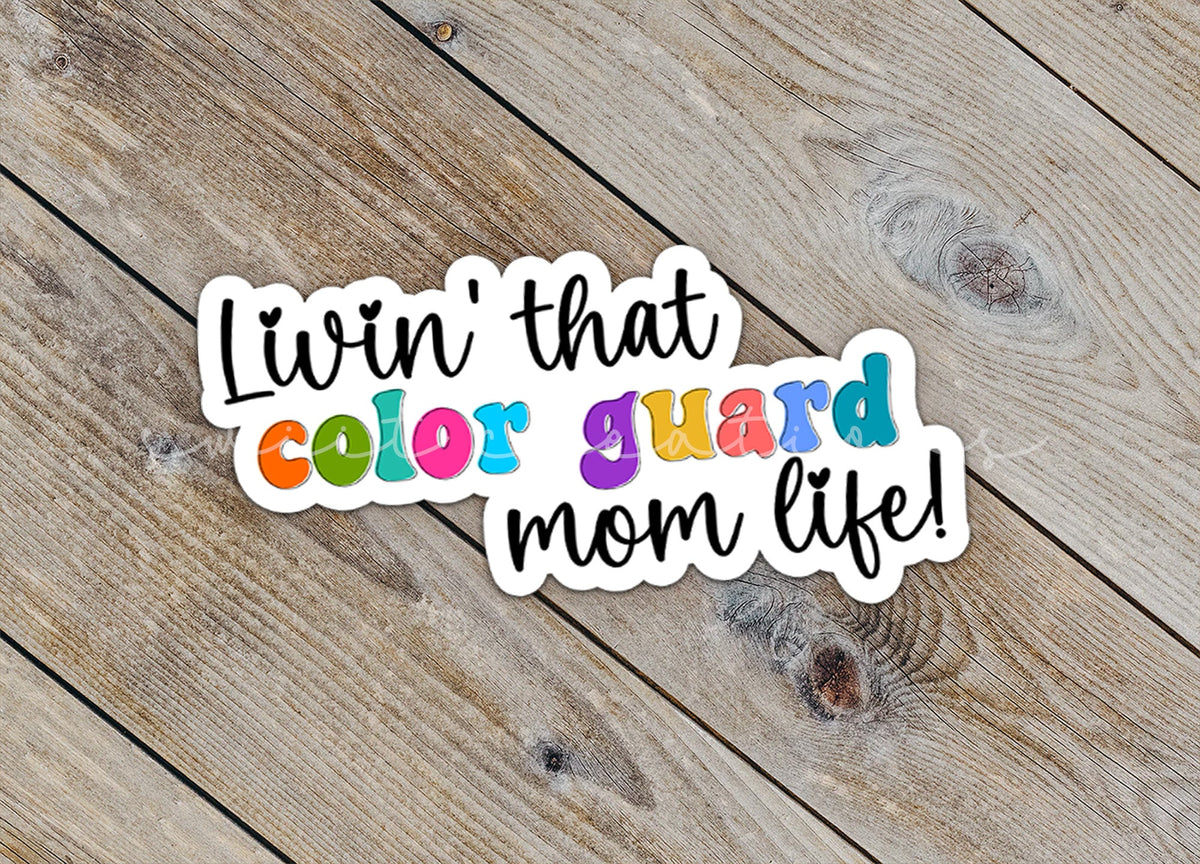 Close-up of the Rainbow Color Guard Mom Life sticker on rustic wood