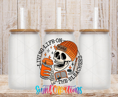 Living Life on the Bleachers skeleton in an orange mama cap UV DTF transfer on frosted glass cans with bamboo lids