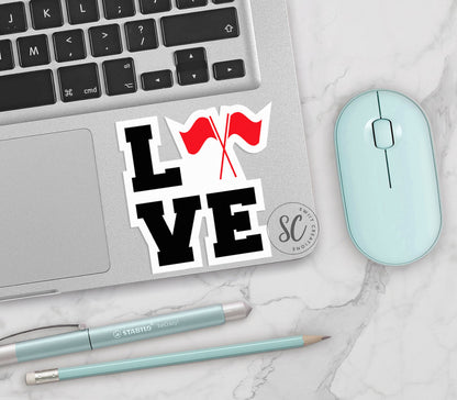 Red Love Color Guard vinyl sticker on a silver laptop next to a mint mouse and pens