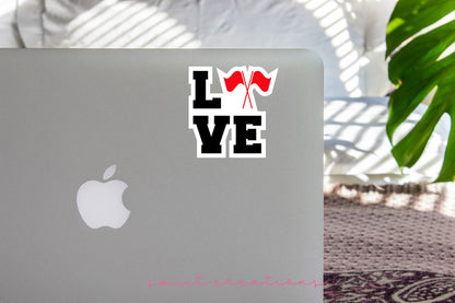 Red Love Color Guard sticker on the lid of a silver laptop