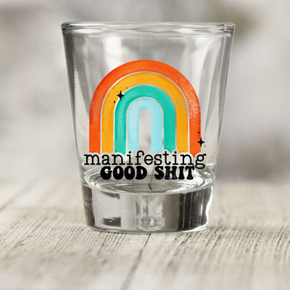 Manifesting Good Sh*t shot glass UV DTF transfer with retro rainbow with star accents on a clear shot glass