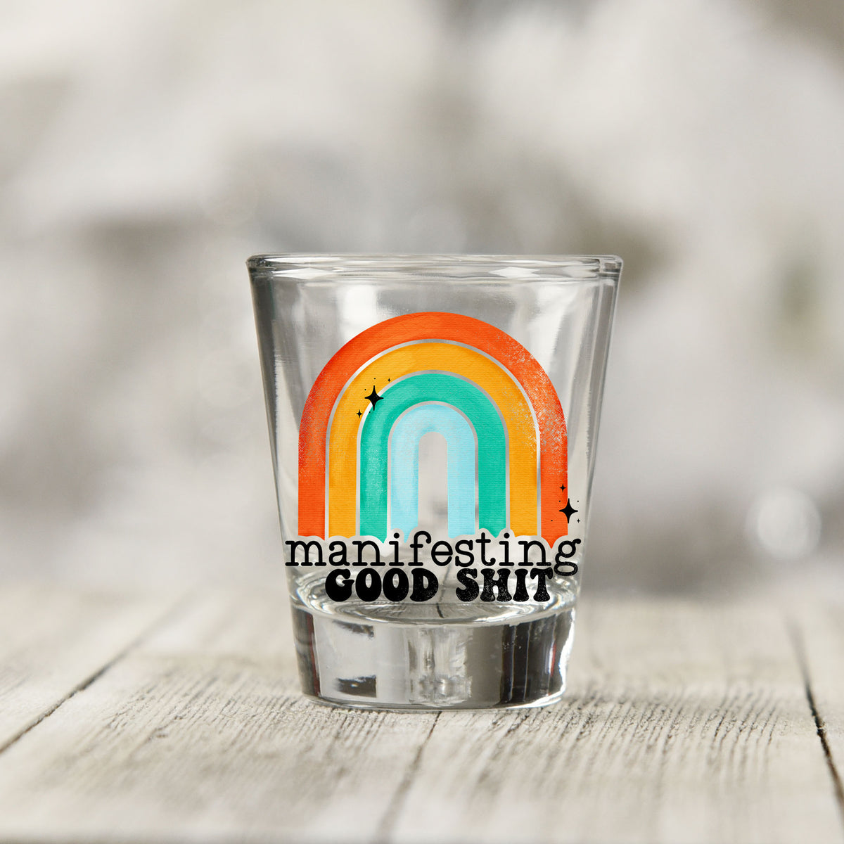 Close-up of the Manifesting Good Sh*t UV DTF transfer on a clear shot glass