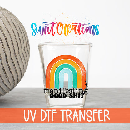 Manifesting Good Sh*t UV DTF transfer on a clear shot glass with the Swiit Creations logo and UV DTF Transfer banner