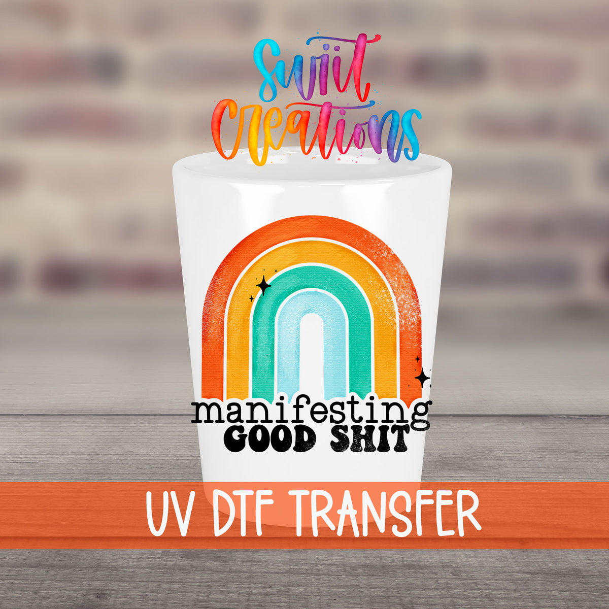 Manifesting Good Sh*t UV DTF transfer on a white shot glass in front of a brick wall