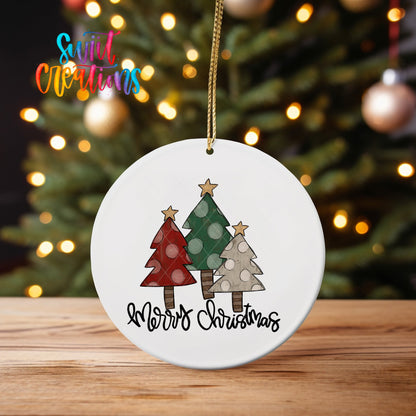 Rustic Tree Trio Merry Christmas ornament UV DTF transfer on an ornament on a wooden table with tree lights behind it