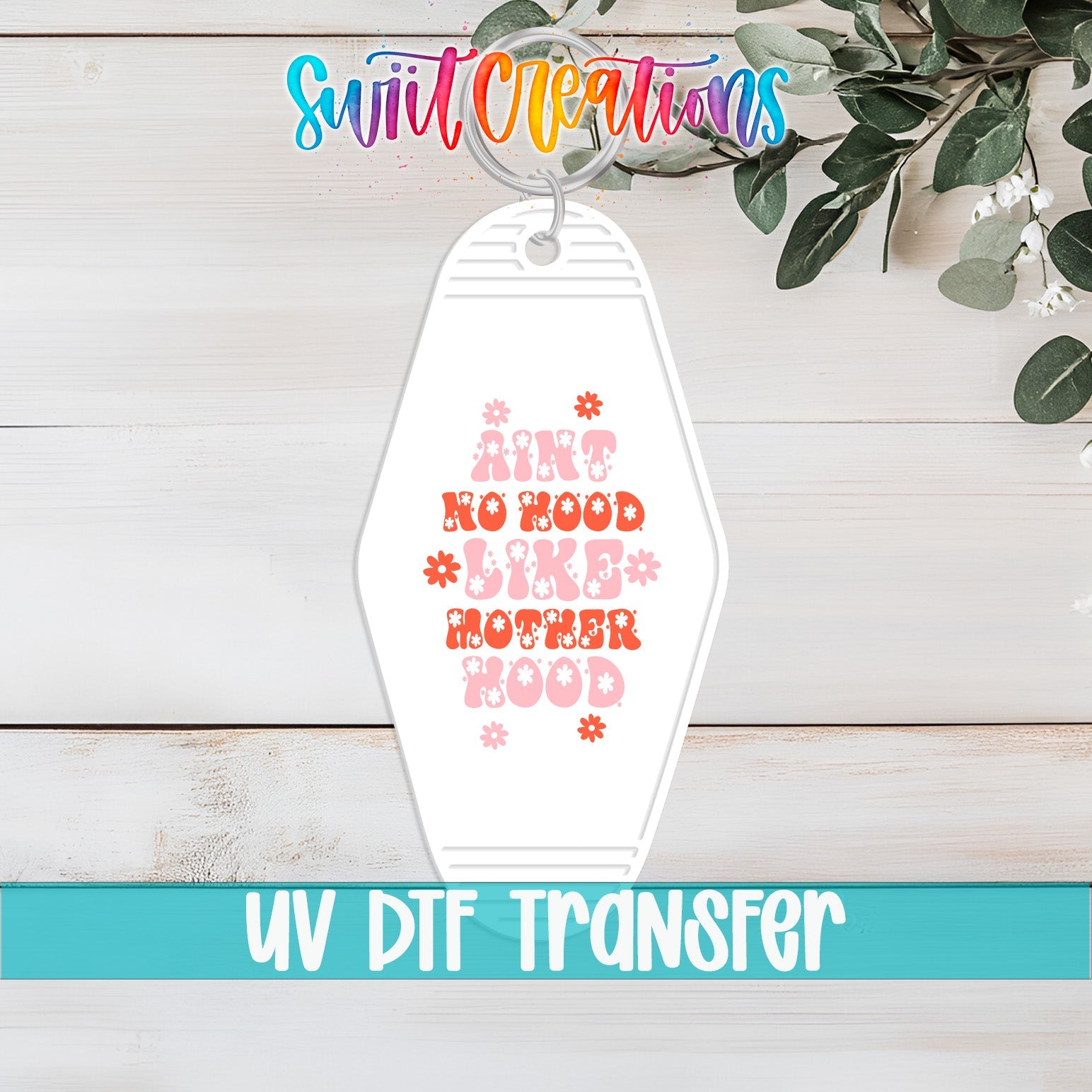 Ain’t No Hood Like Motherhood floral UV DTF transfer on a white motel keychain flat lay