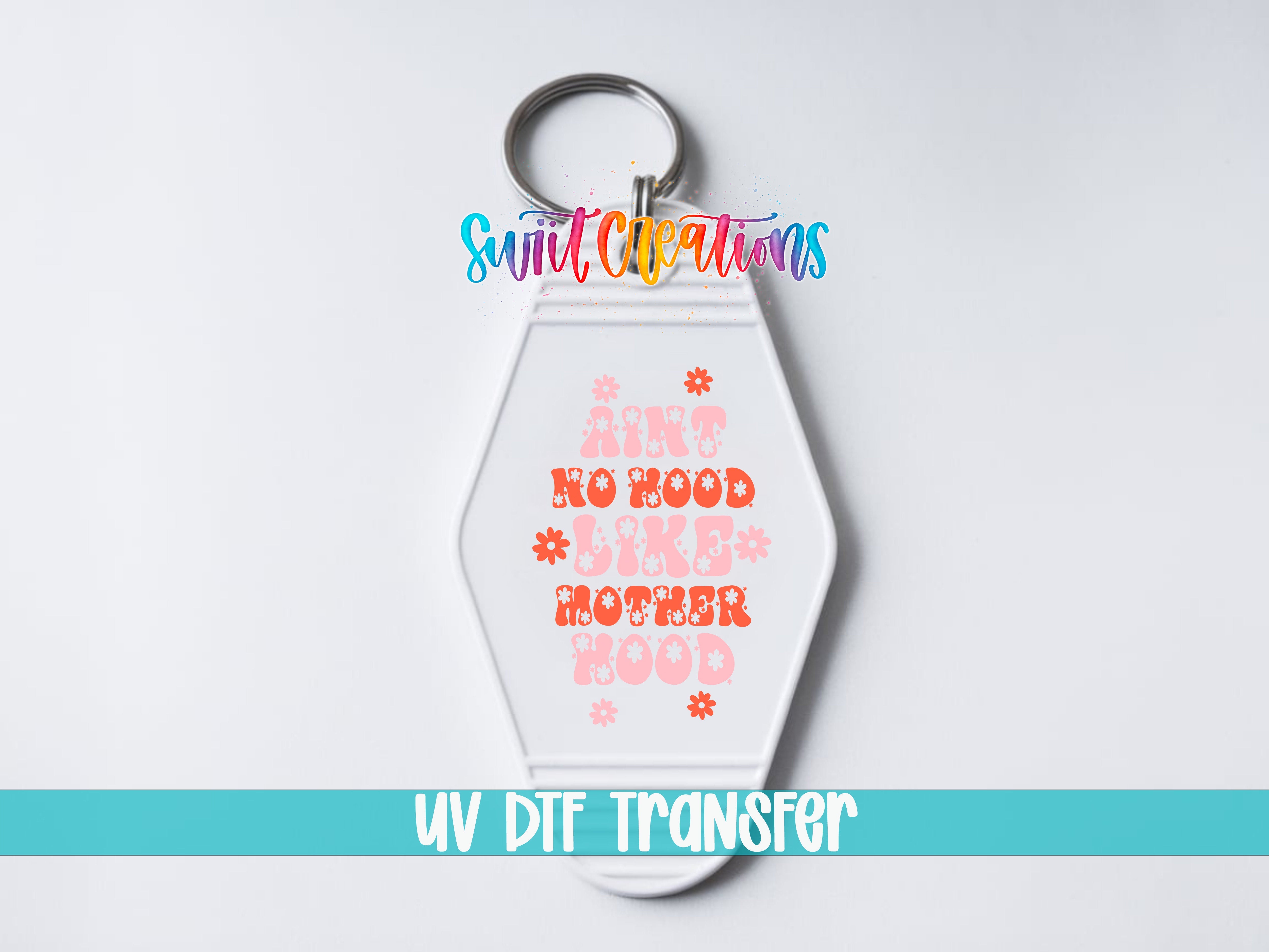 Close-up of Ain’t No Hood Like Motherhood UV DTF transfer on a white motel keychain