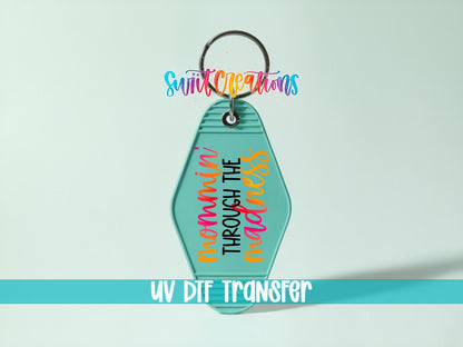 Mommin' Through the Madness UV DTF transfer on a teal motel keychain on a mint background