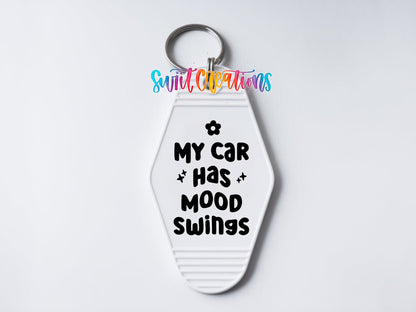 Close-up of the My Car Has Mood Swings UV DTF transfer on a white motel keychain
