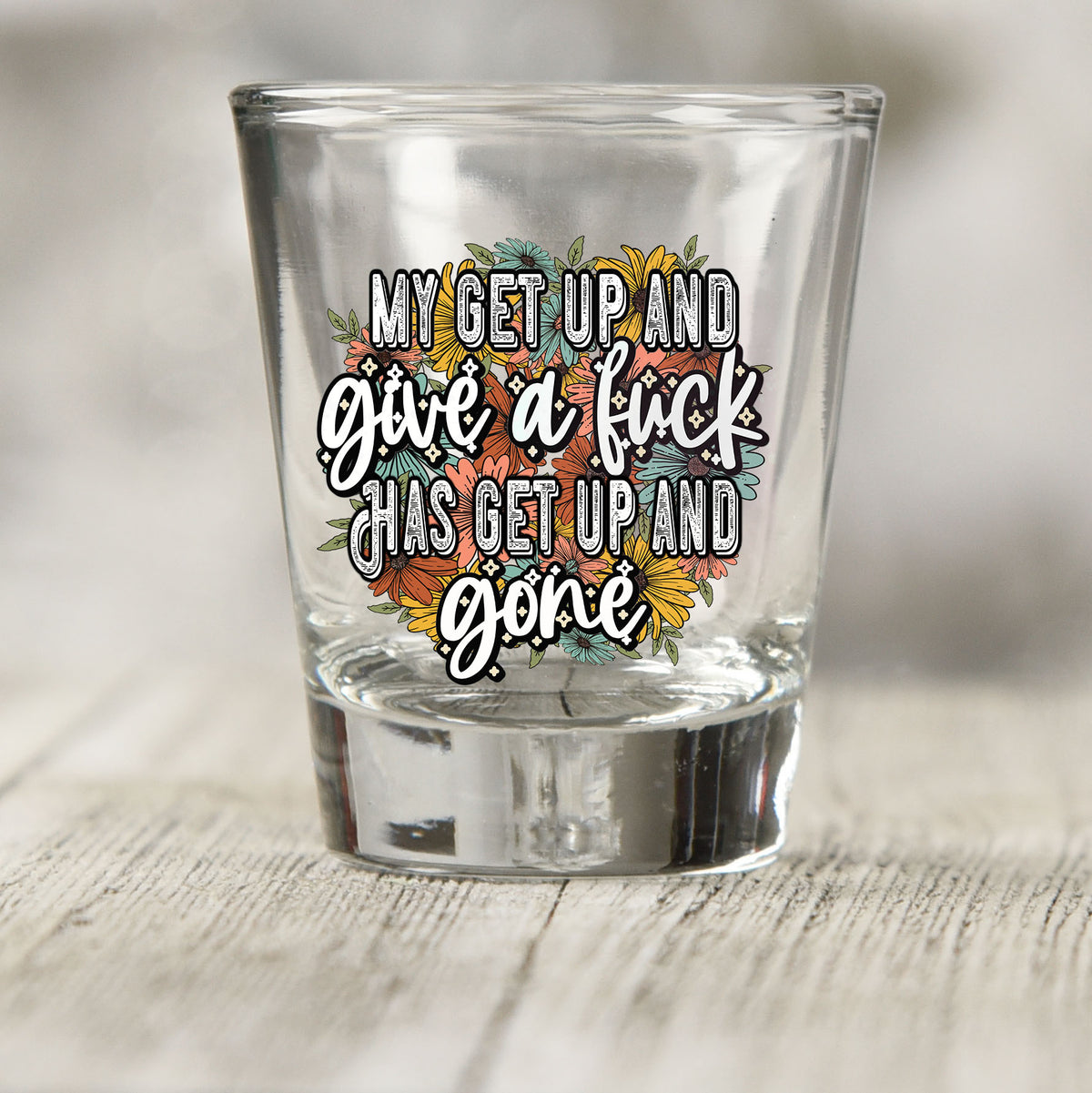 My Get Up and Give a F*ck shot glass UV DTF transfer with orange, teal, and yellow floral background on a clear shot glass