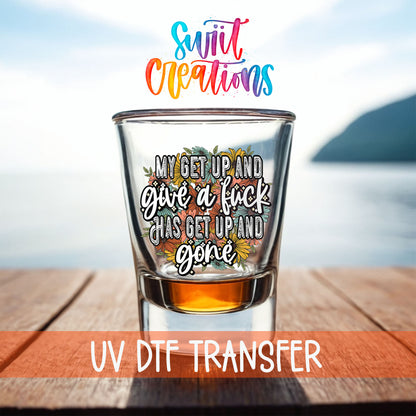My Get Up and Give a F*ck shot glass UV DTF transfer on a filled shot glass on a dock by the water