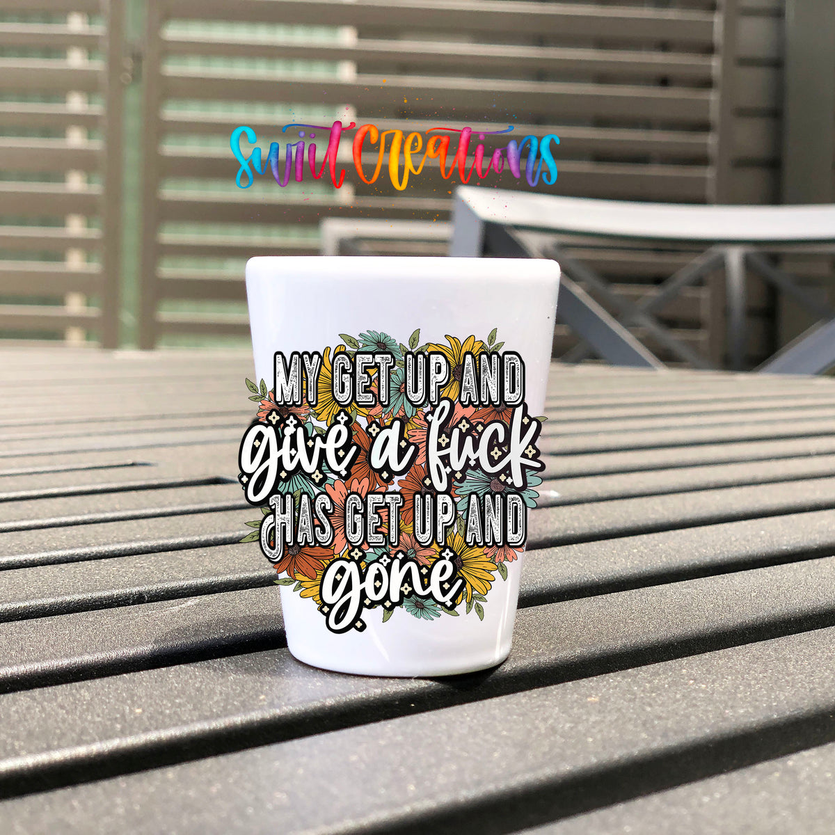My Get Up and Give a F*ck UV DTF transfer on a white shot glass on an outdoor patio table