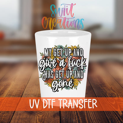 My Get Up and Give a F*ck shot glass transfer on a white shot glass on a wooden table
