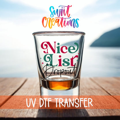Nice List Dropout Christmas shot glass UV DTF transfer on a filled shot glass on a dock by the water