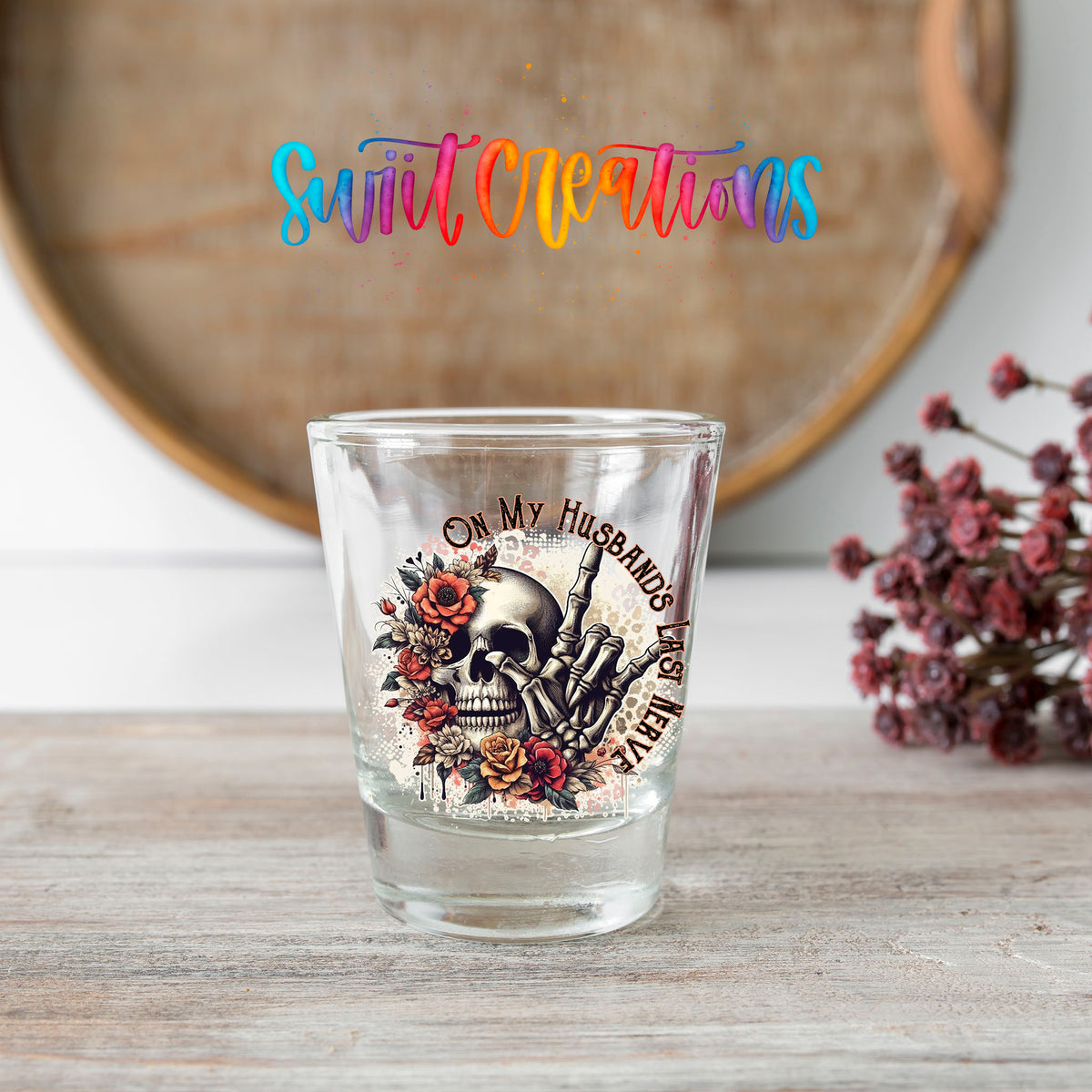 On My Husband's Last Nerve shot glass transfer on a clear glass beside a wooden barrel and dried flowers