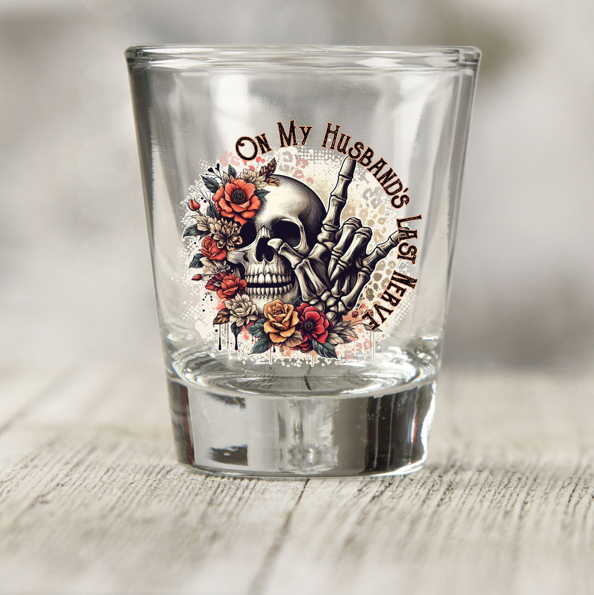 On My Husband's Last Nerve shot glass UV DTF transfer with skull, skeleton hand, and roses on a clear shot glass