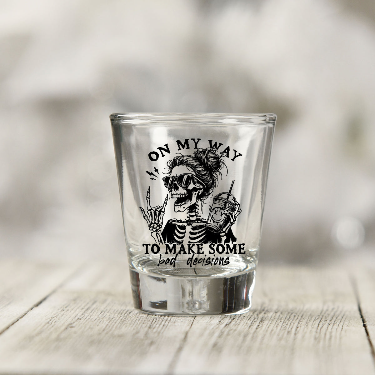 Close-up of the On My Way to Make Bad Decisions UV DTF transfer on a clear shot glass