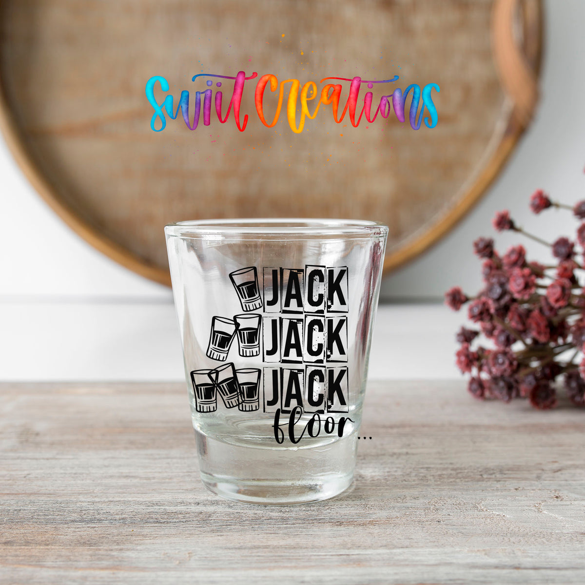 One Jack Two Jack Three Jack Floor shot glass transfer on a clear glass beside a wooden barrel and dried flowers