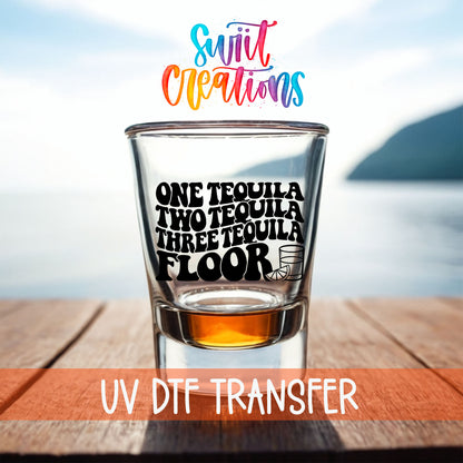 One Tequila Two Tequila shot glass UV DTF transfer on a filled shot glass on a dock by the water