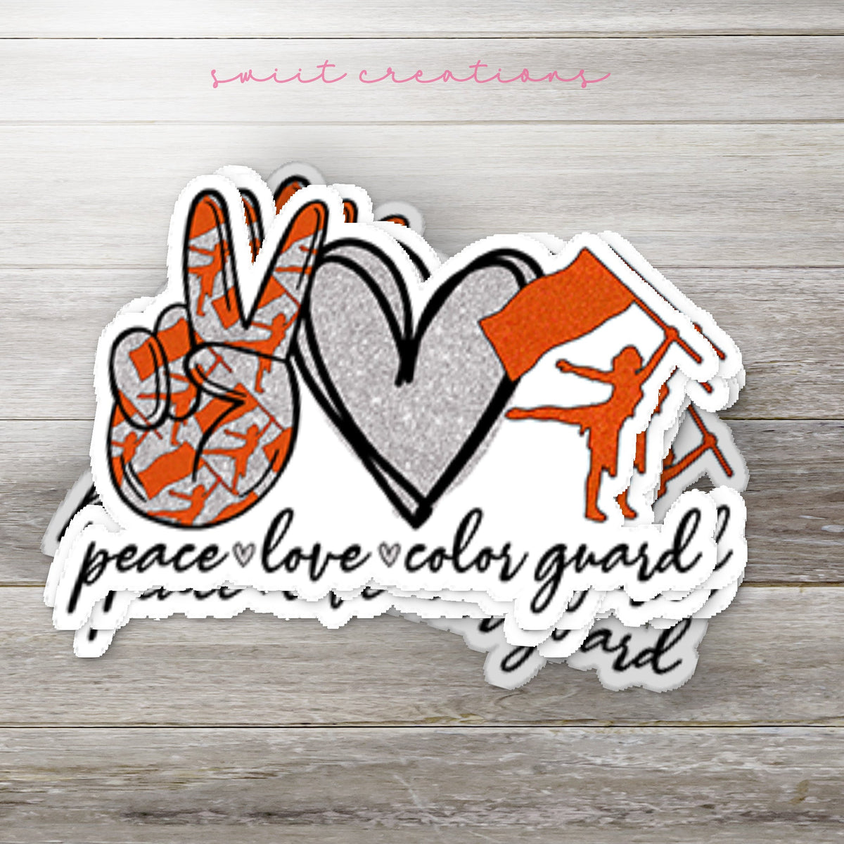 Stack of Orange Peace Love Color Guard glossy stickers on a gray wood table