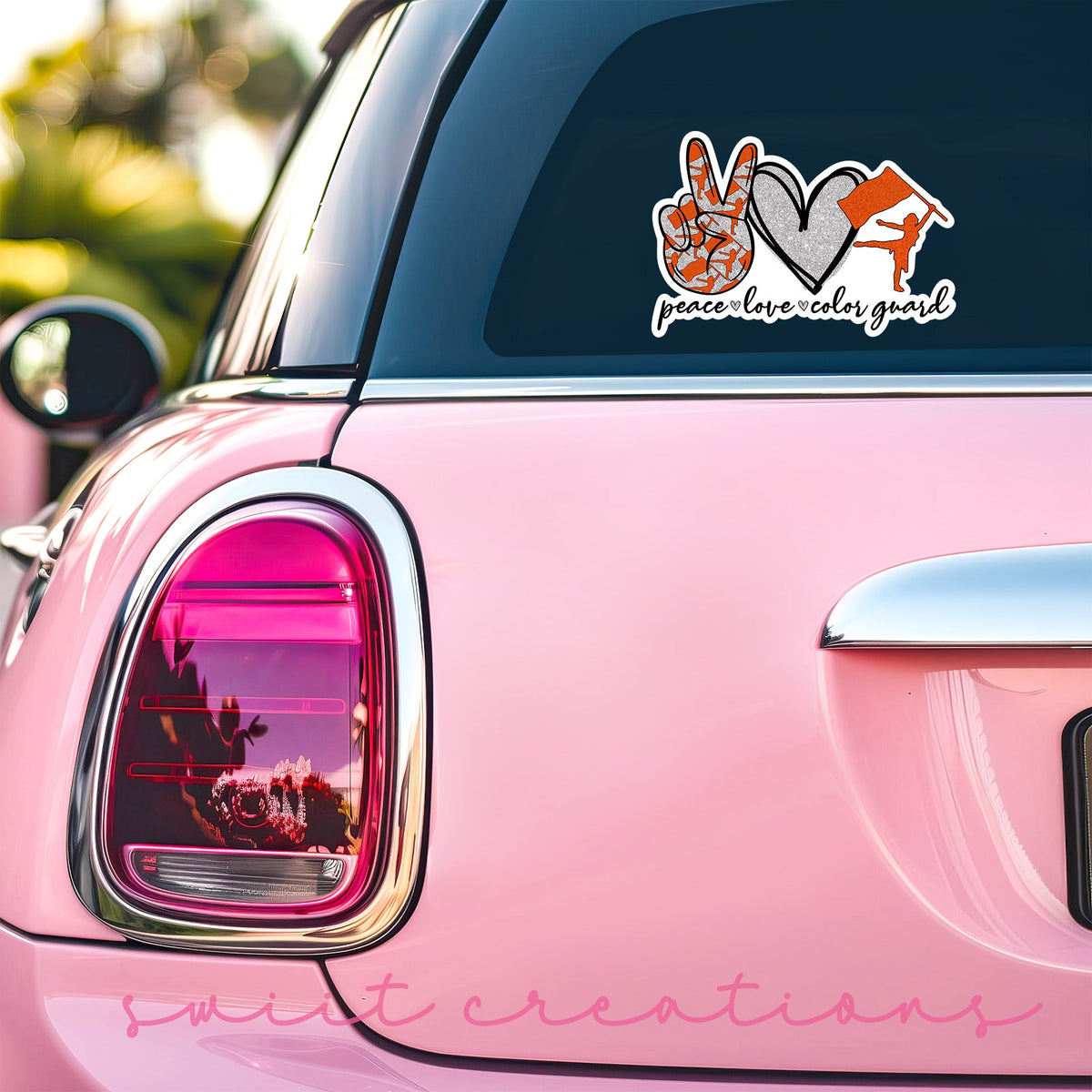 Orange Peace Love Color Guard sticker on the back window of a pink car