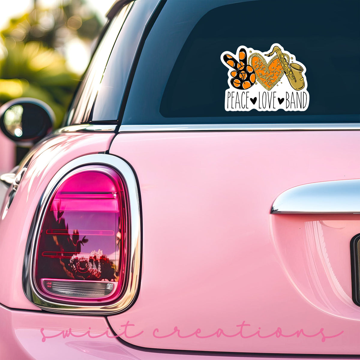 Peace Love Band Saxophone sticker on the back window of a pink car