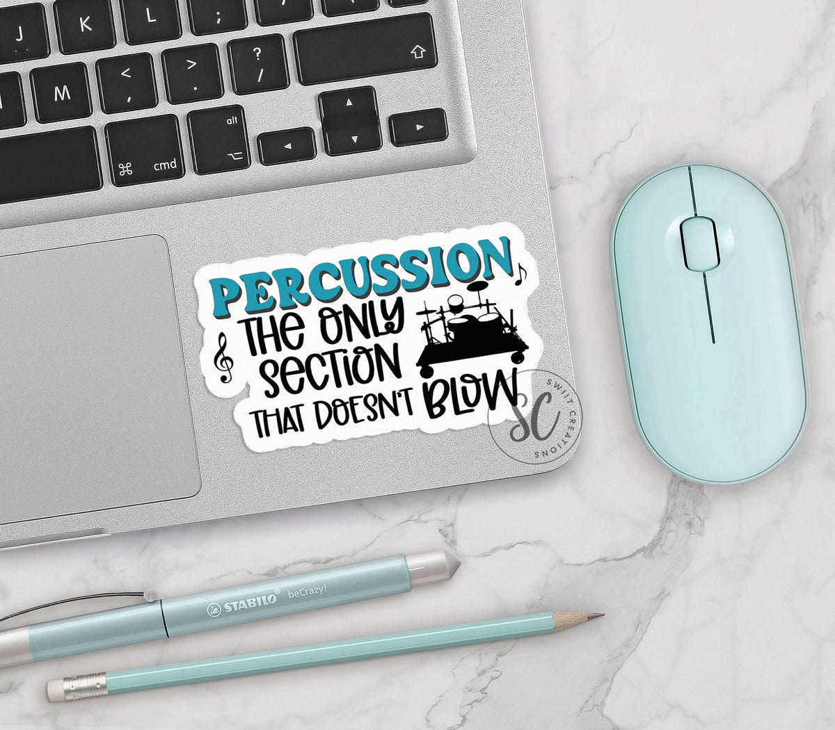 Percussion Doesn't Blow vinyl sticker on a silver laptop next to a mint mouse and pens