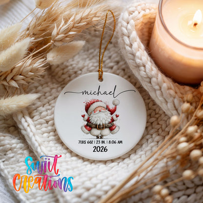 Personalized Baby’s First Christmas Santa Birth Stats ceramic ornament beside a lit candle and knit blanket