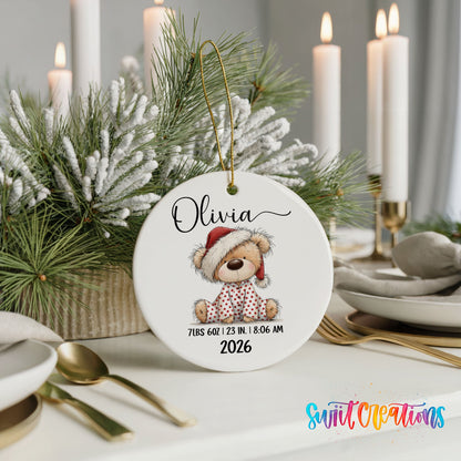 Personalized Baby’s First Christmas Santa Hat Teddy Bear ceramic ornament on a holiday table with candles and greenery