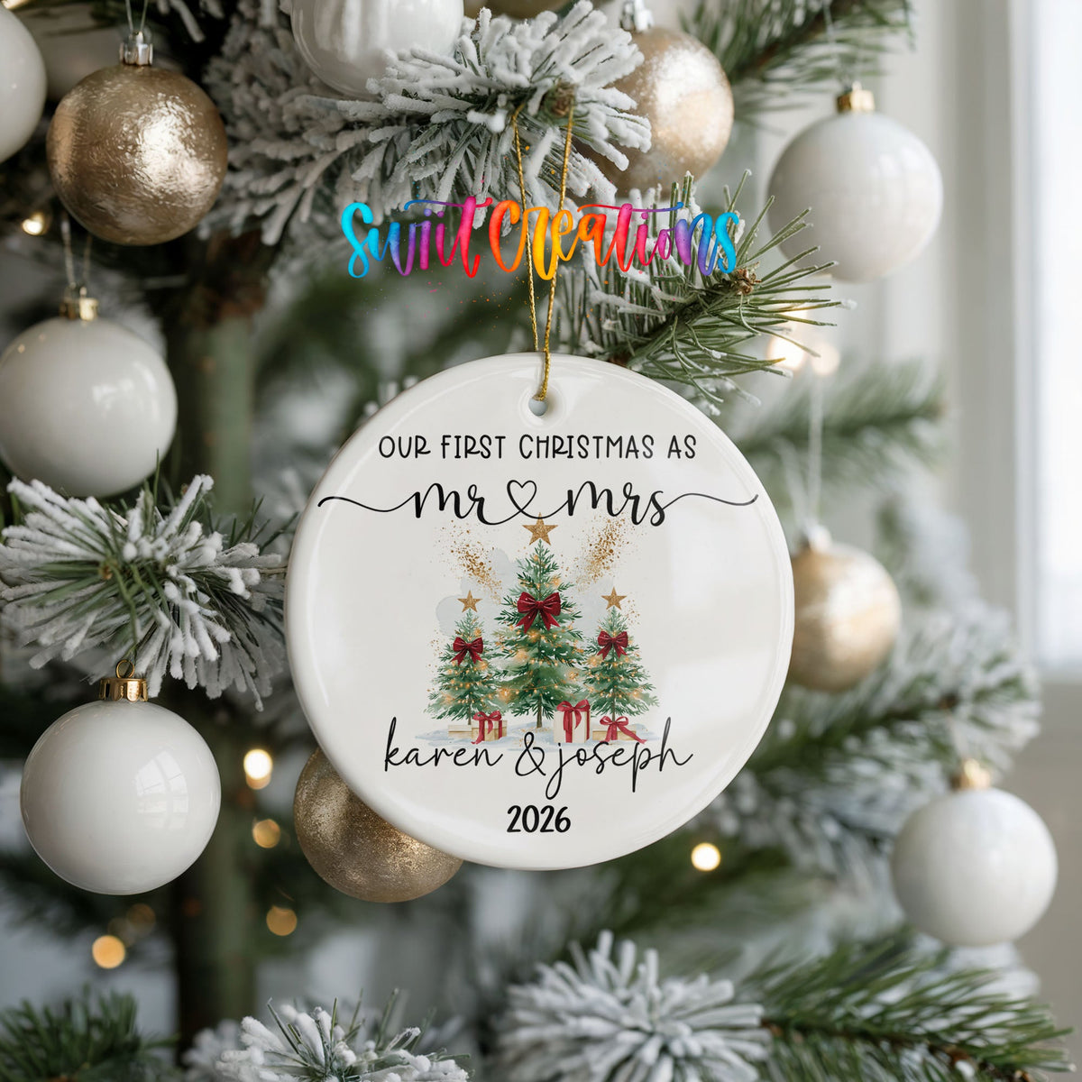 Personalized Our First Christmas Watercolor Tree Couple ceramic ornament hanging on a frosted tree with white ornaments