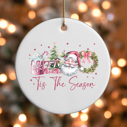 Pink Tis the Season Santa ornament UV DTF transfer on a round white ornament with a bokeh light background