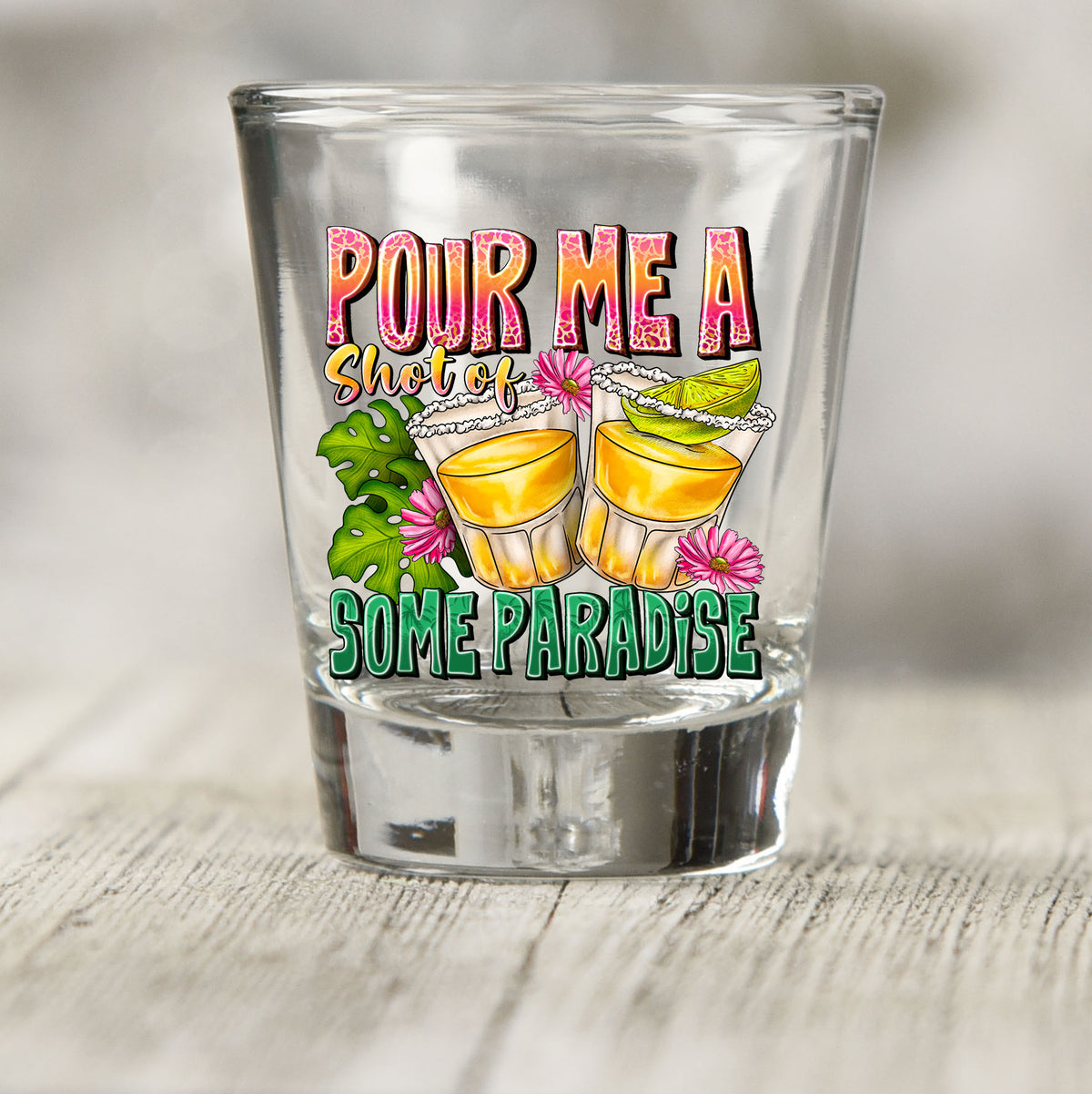 Pour Me a Shot of Some Paradise shot glass UV DTF transfer with tequila shots with limes, leaves, and flowers on a clear shot glass