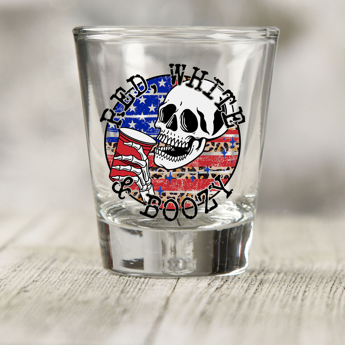 Red White and Boozy shot glass UV DTF transfer with skull with a red cup, flag, and leopard print on a clear shot glass