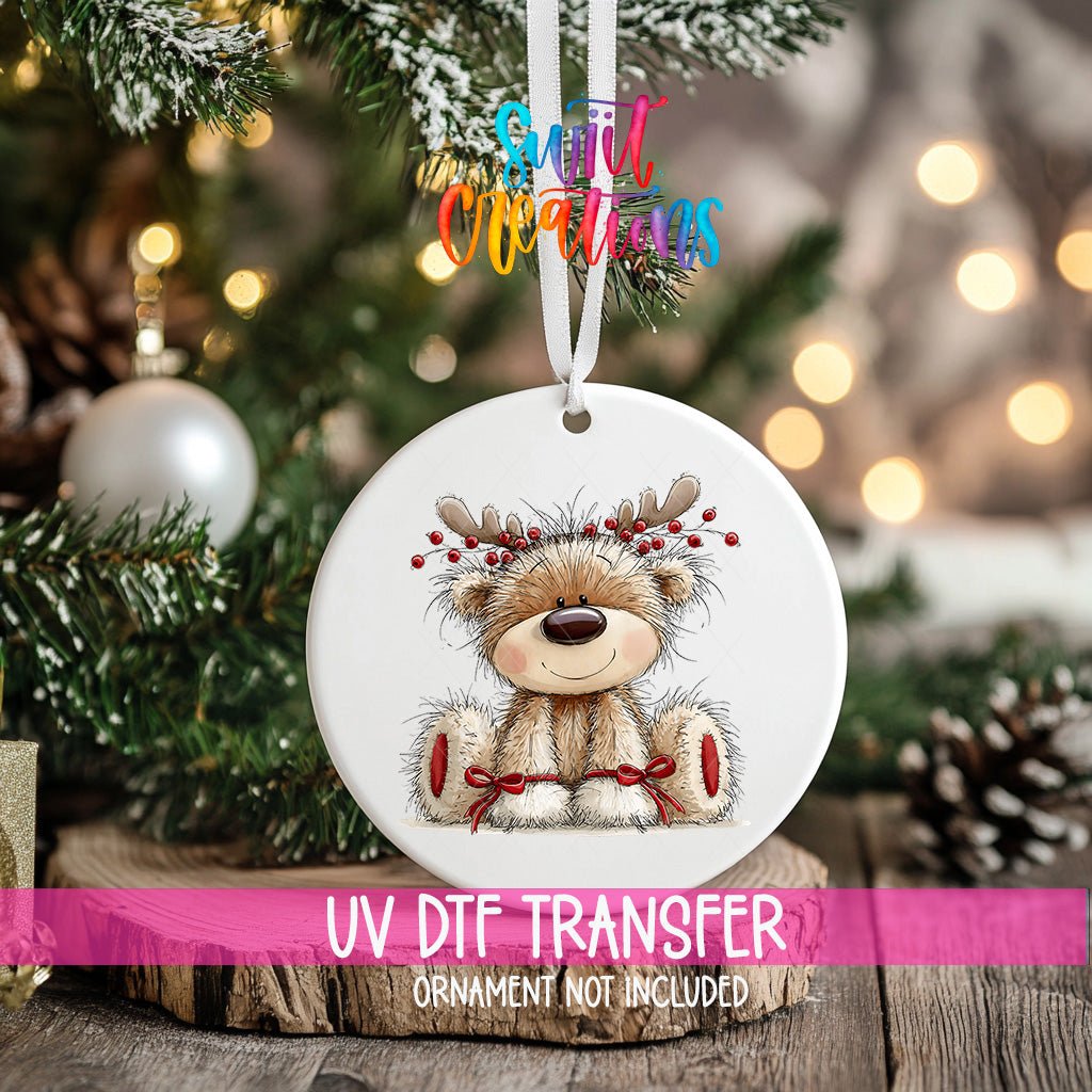 Reindeer Teddy Bear ornament UV DTF transfer on an ornament resting on a wood slice beside a Christmas tree