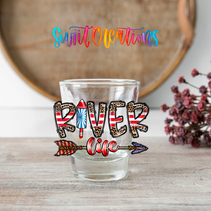 River Life USA shot glass transfer on a clear glass beside a wooden barrel and dried flowers