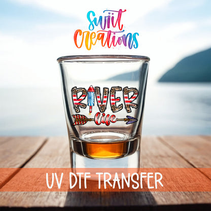 River Life USA shot glass UV DTF transfer on a filled shot glass on a dock by the water