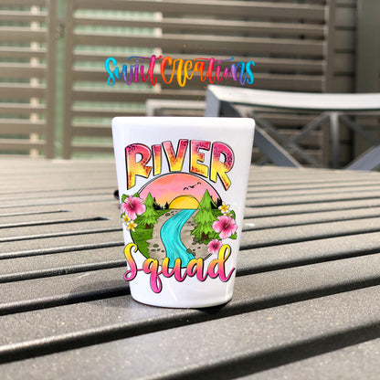 River Squad UV DTF transfer on a white shot glass on an outdoor patio table