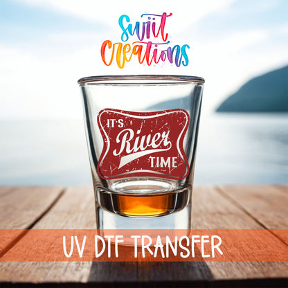 River Time shot glass UV DTF transfer on a filled shot glass on a dock by the water