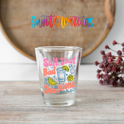 Salt Shot Bad Decisions shot glass transfer on a clear glass beside a wooden barrel and dried flowers