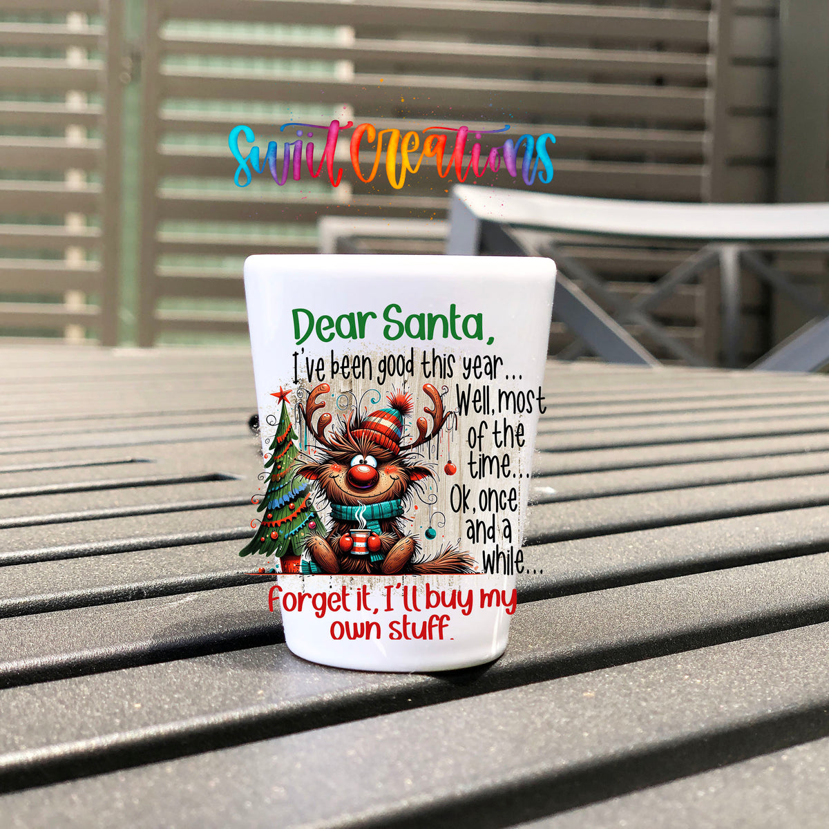 Santa I've Been Good Christmas UV DTF transfer on a white shot glass on an outdoor patio table