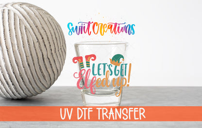 Let's Get Elfed Up Christmas elf shot glass UV DTF transfer shown on a clear shot glass beside a ribbed vase with an orange UV DTF Transfer banner.